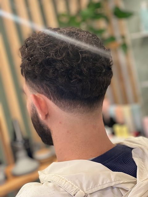 Low taper fade on curly hair.